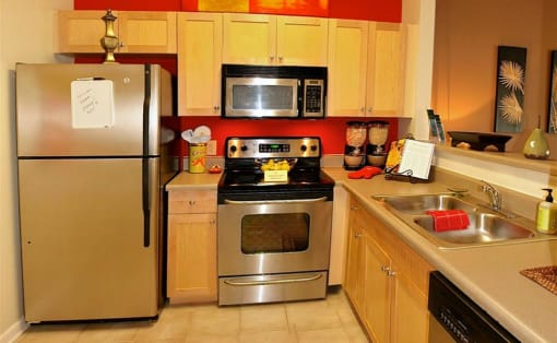 a kitchen with stainless steel appliances and wooden cabinets at Chester Village Green Apartments, Chester, VA, 23831