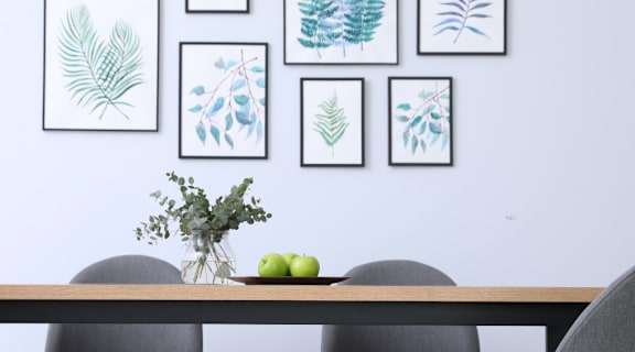 A dining table with four grey chairs and a vase of flowers on it.