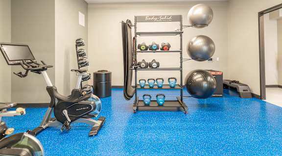 A gym room with a blue floor and a variety of exercise equipment.at Vista Apartments at Edgemont, Alberta, T6M 1J4