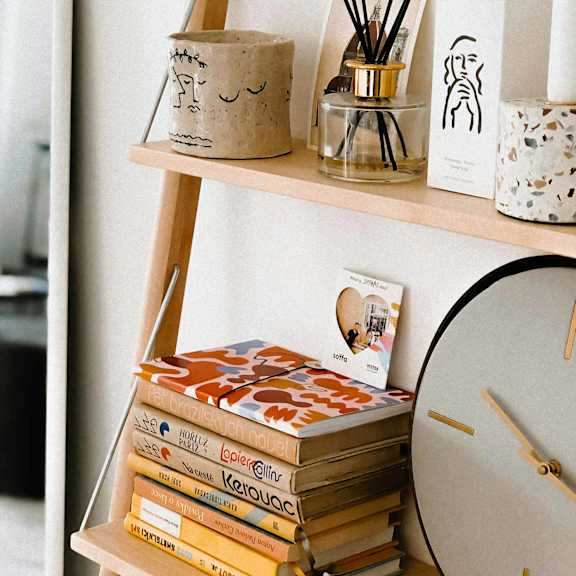 Home decor of a shelf with books, a clock, and a diffuser