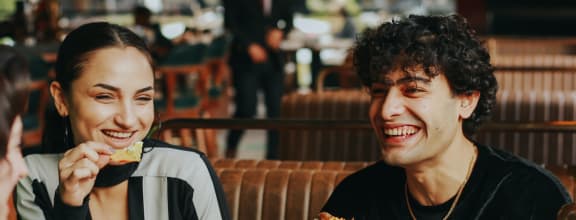 group of people eating pizza in a restaurant