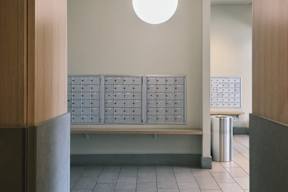 A white circular light hangs from the ceiling in a hallway with a bench and a trash can.