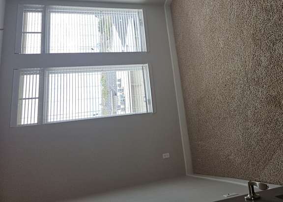 A room with a window and a carpeted wall.