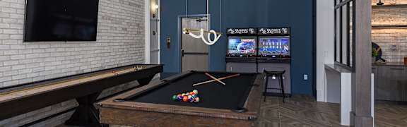 A pool table in a room with a brick wall and a television.