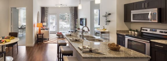 an open kitchen and living room with a large granite counter top