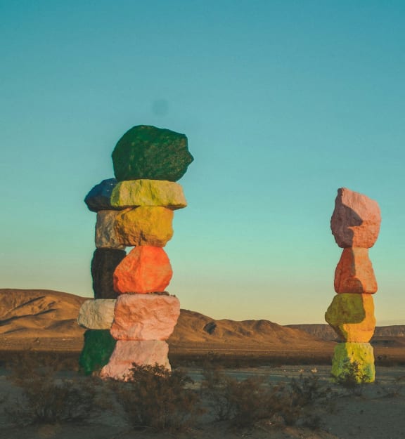 a group of totem poles in the desert against a blue sky