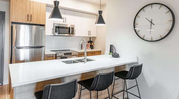 A modern kitchen with a large island and a clock on the wall.