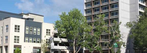 A tall white building stands next to a shorter grey building at Denver Metro Village Apartments, Denver, CO