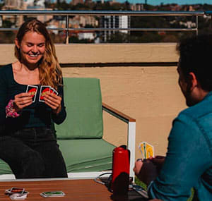 a woman is sitting at a table holding two cards