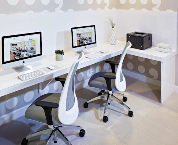 a white office with two computer monitors and two chairs