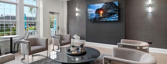 A modern living room with a large screen TV and comfortable seating.