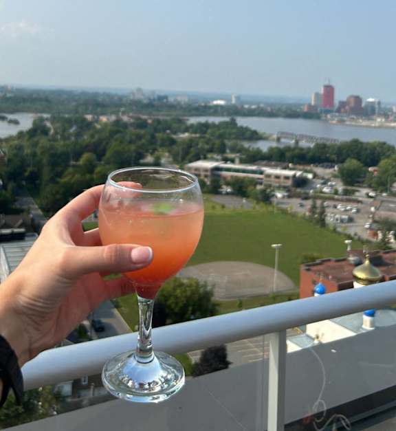 a glass of orange juice on a balcony overlooking a city