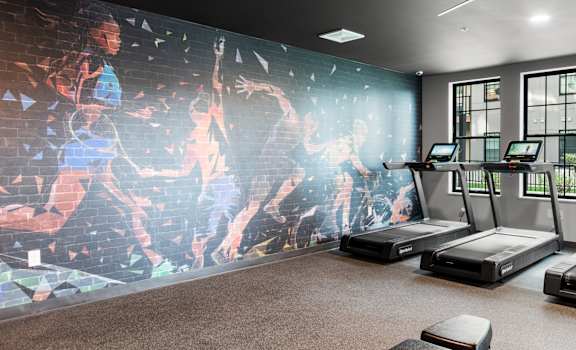a fitness room with treadmills and a large wall mural of a map