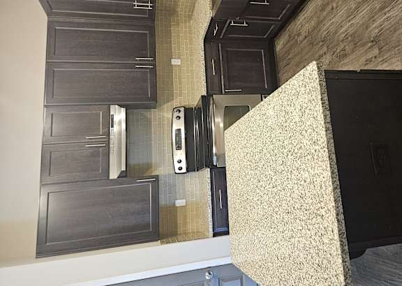 A kitchen with a black oven and a wooden wall.