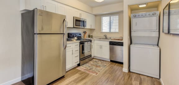 Kitchen with stainless appliances including microwave and stackable Washer & Dryer. 