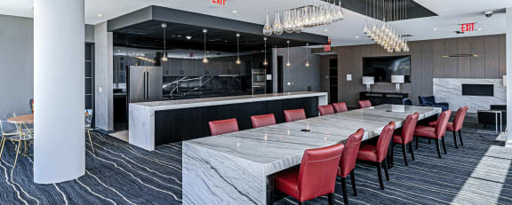 Elegant communal kitchen at 3THIRTY3 Apartments, featuring a large marble island, red leather chairs, and a modern design, showcasing a luxury space for residents.