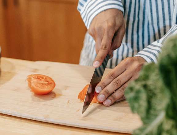 A person cutting a lemon on a wooden cutting board.