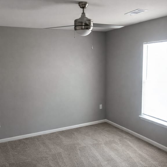 A room with a ceiling fan and a window.