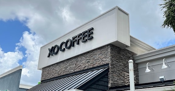 The front of a coffee shop with the name XOCOFFEE on the building. at The Teale, Kissimmee, FL, 34746