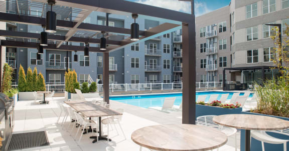 an outdoor patio with tables and a pool at an apartment building