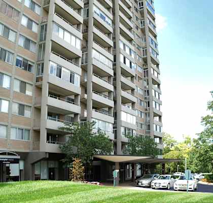 A tall residential building with a parking lot in front.