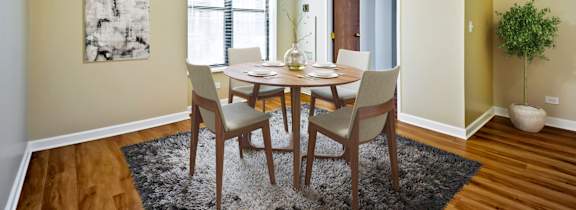 A dining room with a table set for two and a plant in a white pot.