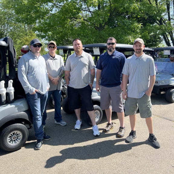 a group of men standing in front of a row of vehicles