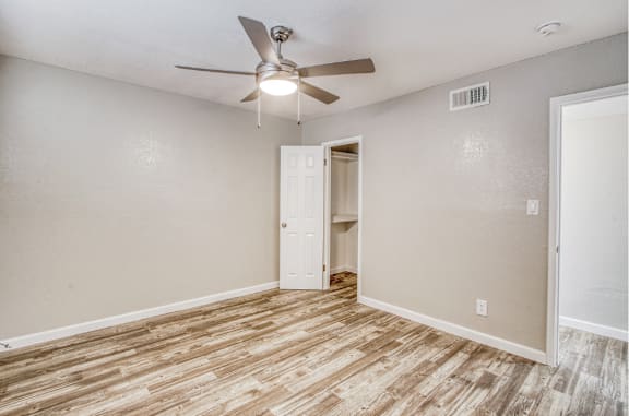 A room with a ceiling fan and wooden flooring.