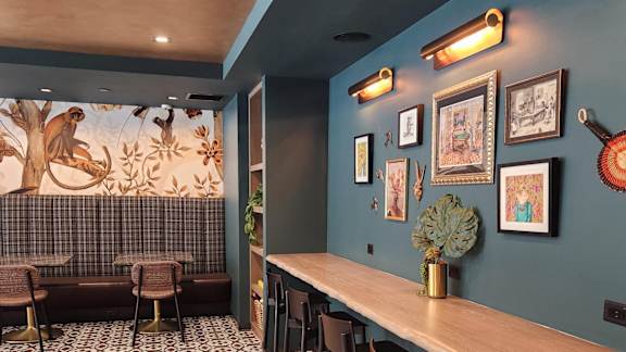 A room with a long table and chairs with a mural of a monkey on the wall.
