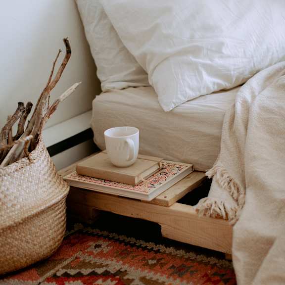 A tray with books and a cup of coffee placed next to a bedroom.