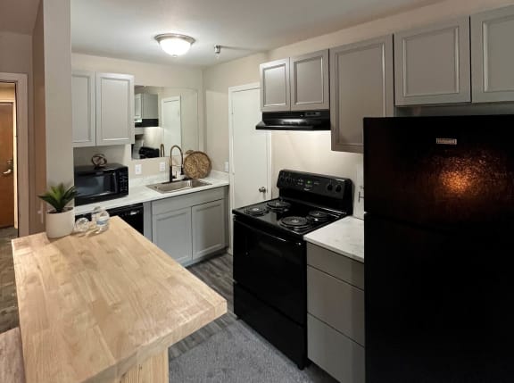 a kitchen with white cabinets and black appliances at The Lodge Apartments, Tulsa, OK