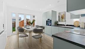 A modern kitchen with a dining table set for six at The Farriers Apartments, Milton Keynes, MK8 1LS
