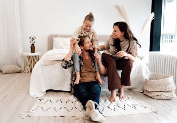 Family of Three Sitting on Floor in a Bright Bedroom