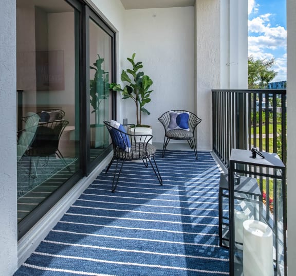 a small balcony with two chairs and a table at Altis Blue Lake, Lake Worth, FL