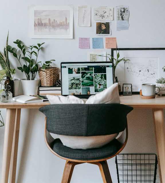 A modern workspace featuring a laptop, chair, and various decorative items.