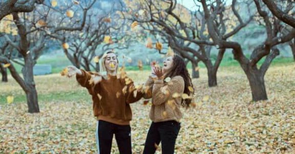 a man and a woman are throwing leaves in the trees