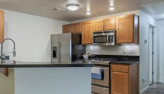 A kitchen with a refrigerator, stove, and bar stools.