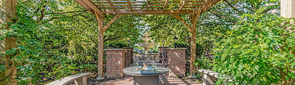 A wooden pergola with a table and chairs under it.