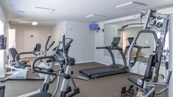 a gym with various exercise machines and a tv in the corner at Crawford Square Apartments