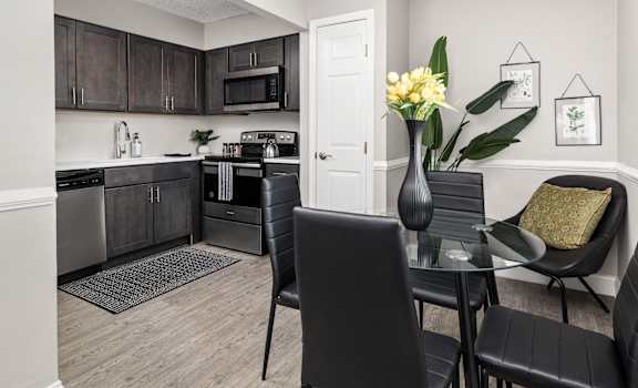 a dining area with a table and chairs and a kitchen in the background