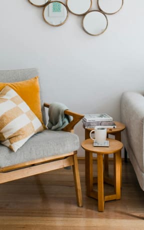 a living room with a couch and a chair and several mirrors on the wall