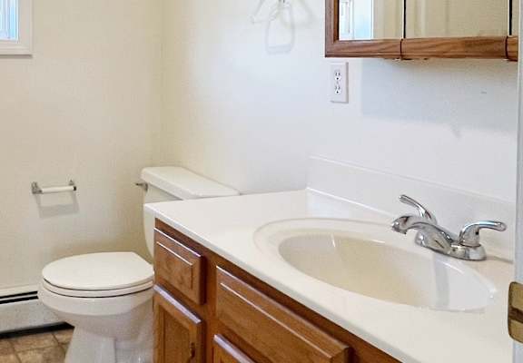 A bathroom with a toilet, sink, and mirror.