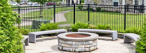 A white house with a black fence and a fire pit in the middle of the yard.