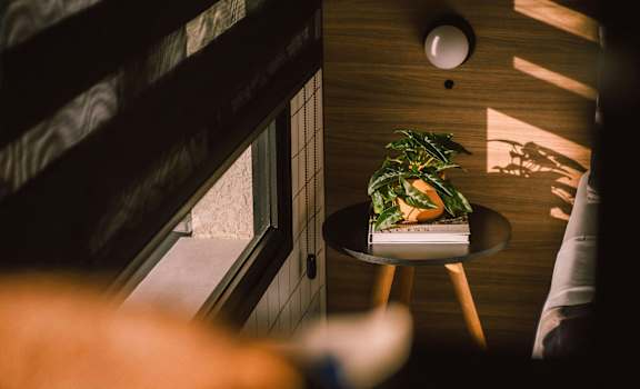 A small round table with a plant on it sits in the corner of a room.
