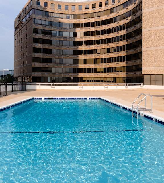 A large building with a curved top and a swimming pool in front at Hampton Plaza Apartments, Towson, MD, 21286