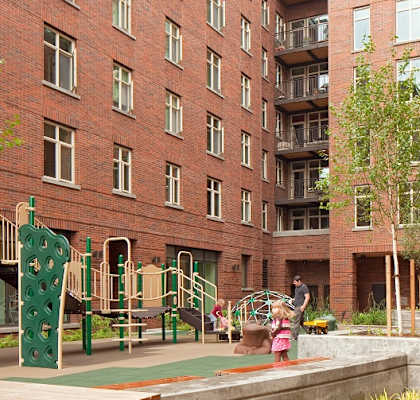 A playground area with a green slide and a person riding a bicycle.