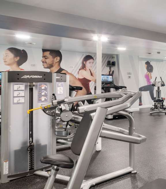 A gym with a variety of equipment and a few people working out.