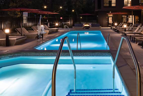 A swimming pool at a resort with lounge chairs and umbrellas.