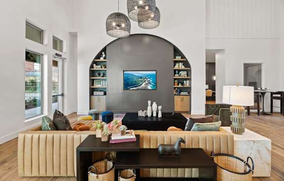 A living room with a large couch, a coffee table, and a TV on the wall.