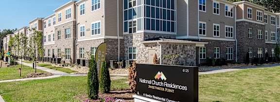 a large building with a sign in front of it on a lawn
